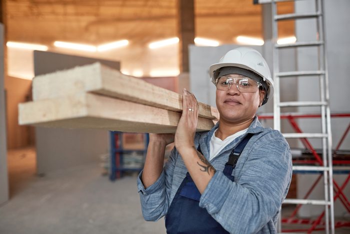 Smiling Female Worker Carrying Wood