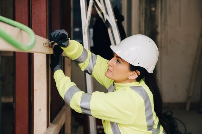 Female engineer marking on wooden plank while working at site
