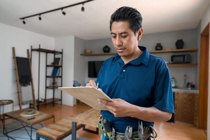 Electrician working at a house and writing a report on a clipboard