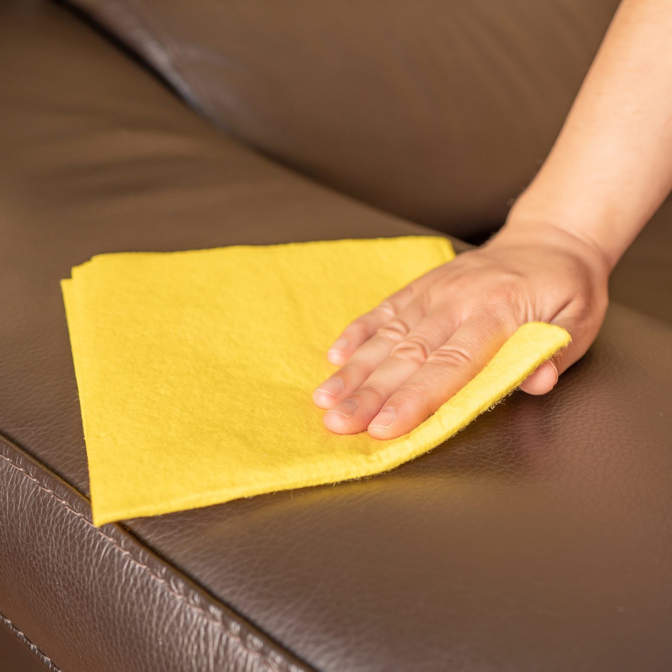 woman cleaning black leather sofa