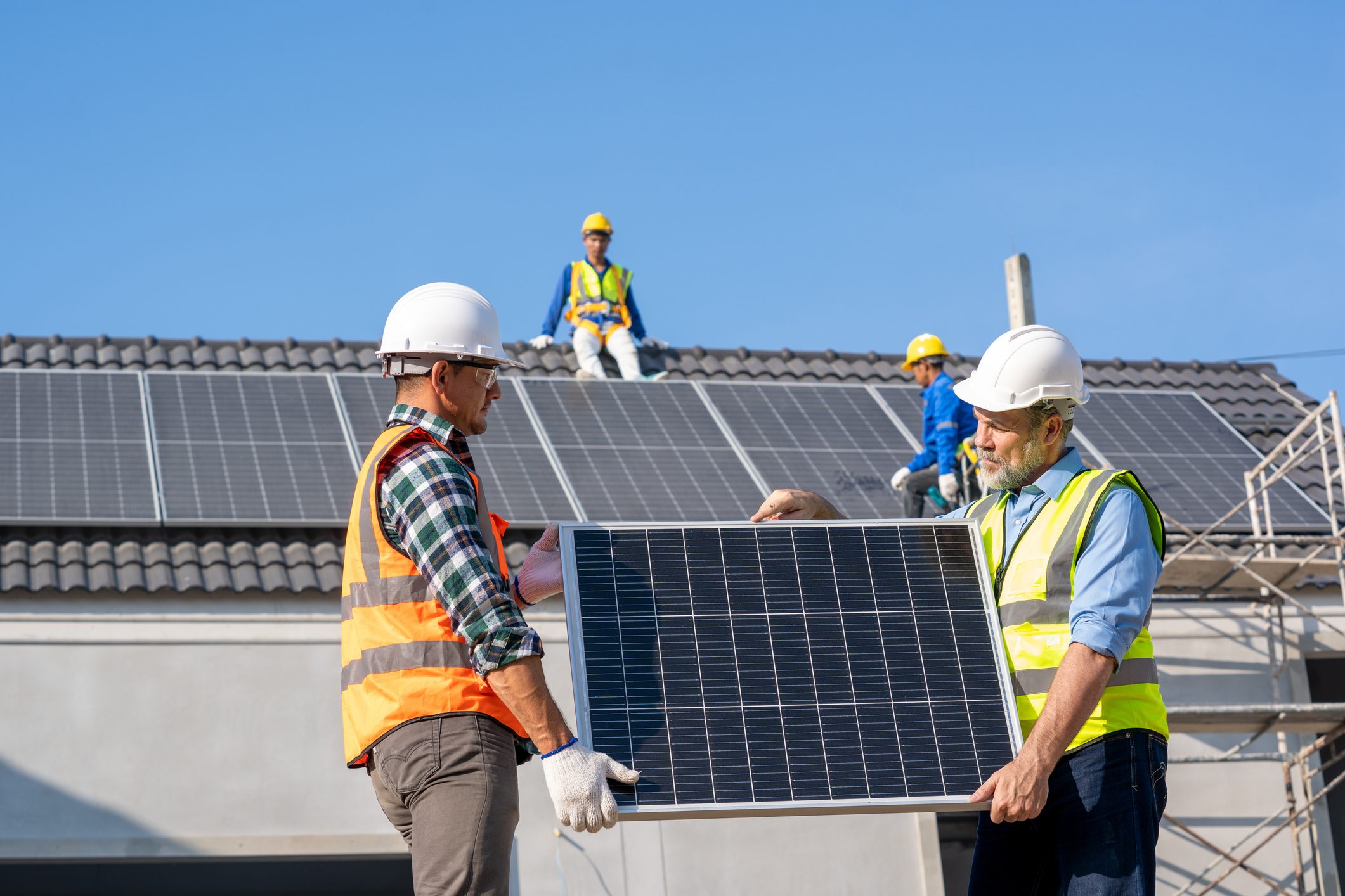 Engineers examining and installer photovoltaic panels at new house.