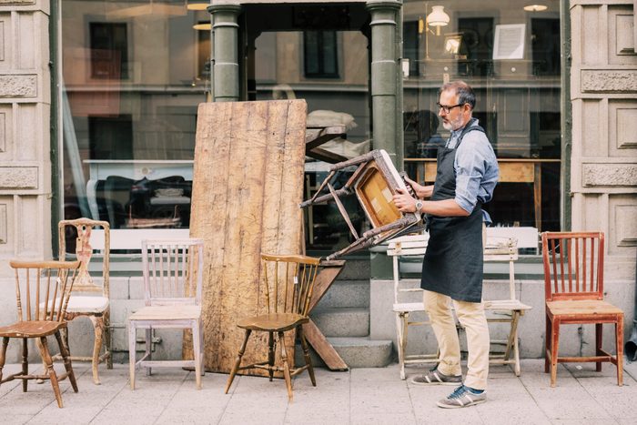 Full length of man holding chair while arranging outside store