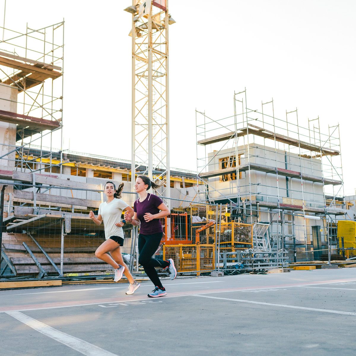 Two Women Jogging past a building construction site Outdoors In The City