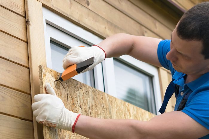 Homeowner Is Blocking The Windows with plywood Before A Natural Disaster