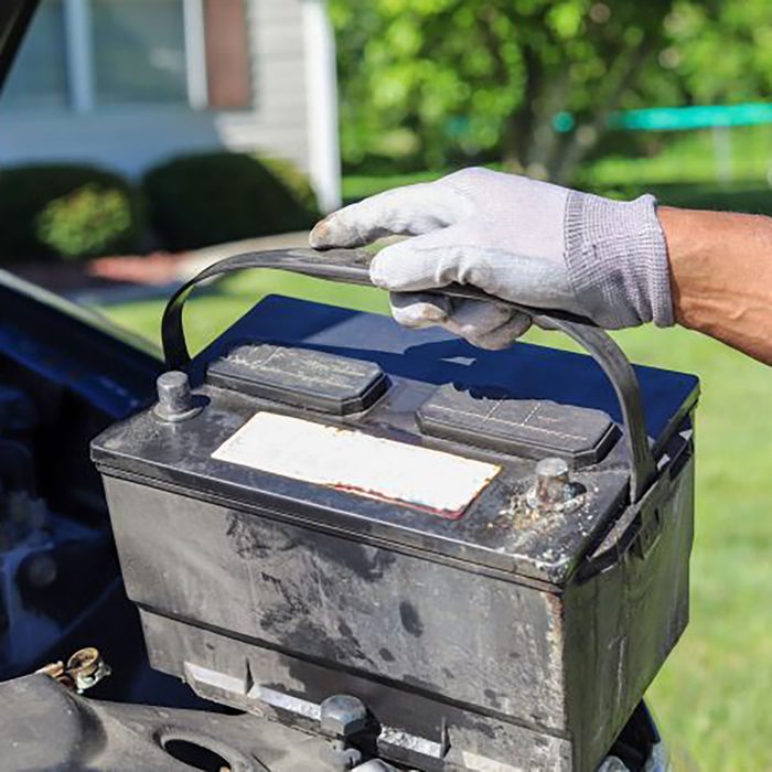man taking a car battery out of a truck