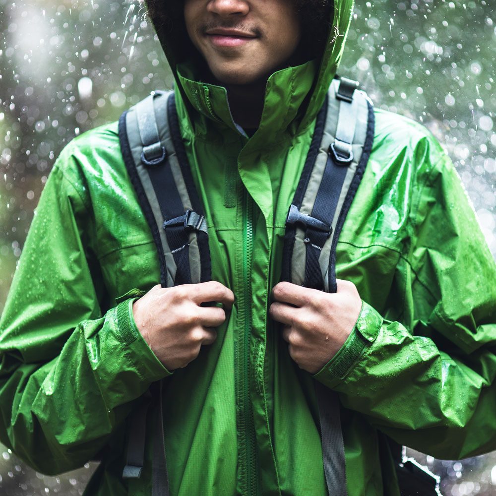 Young Man Hiking In Rain With Waterproof Jacket