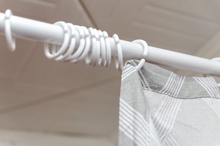 Close-up of an incomplete hanging a gray curtain in the bathroom shower