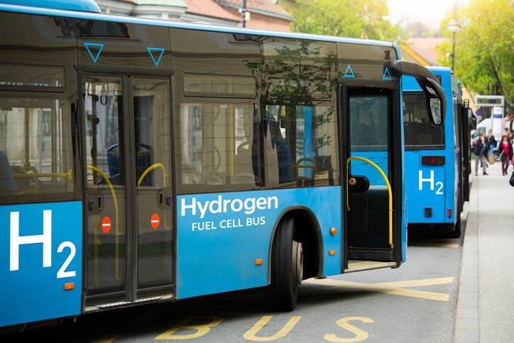 hydrogen fuel cell buses stop at local bus station for passengers to enter and exit the bus