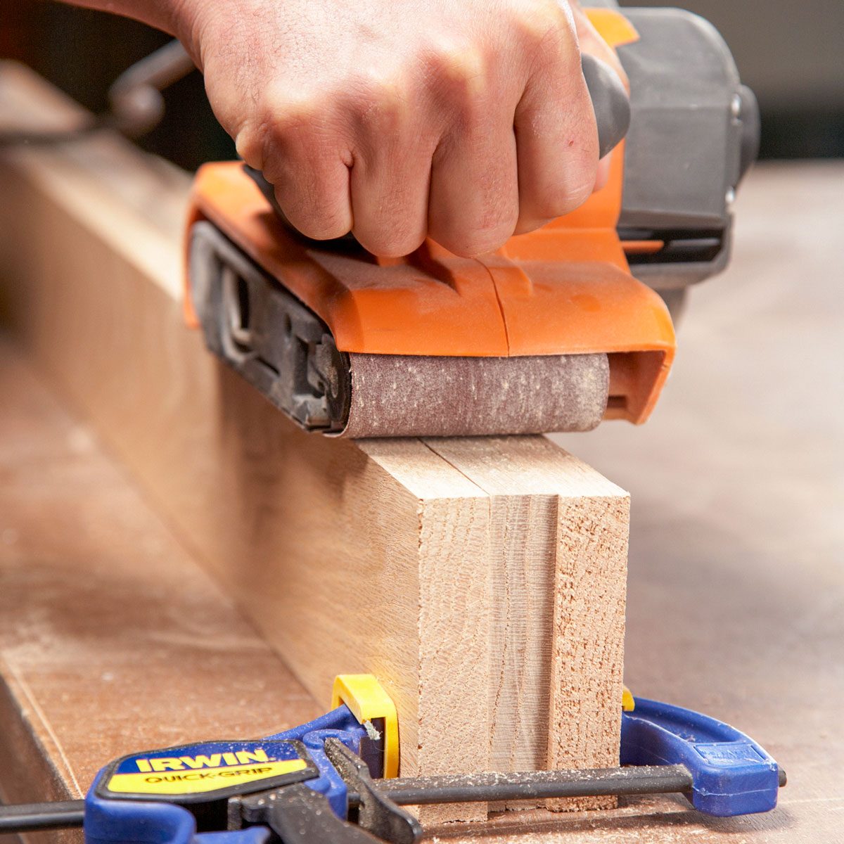 A Man Sanding Couple of Woods With Sander