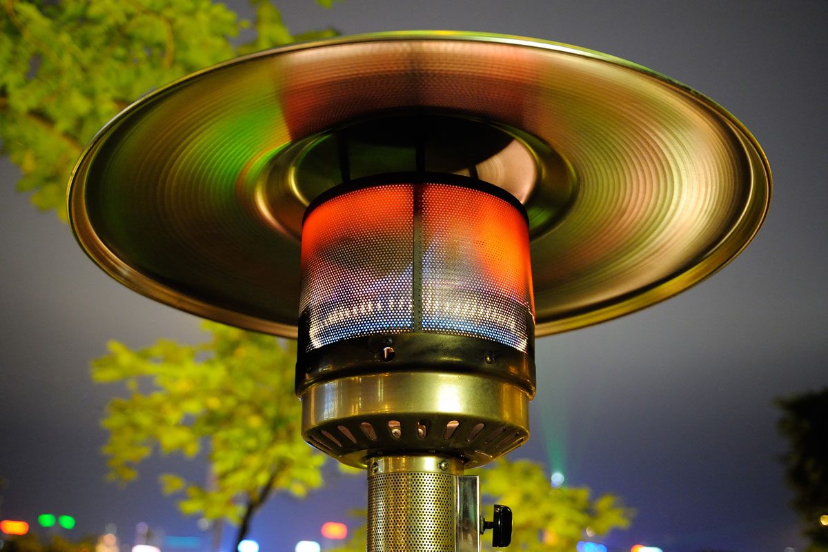 Close up at radiant outdoor gas heater working at night in the street restaurant.