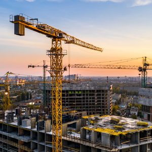 Construction Site of an apartment building seen pictured at sunset with construction cranes erected in the background