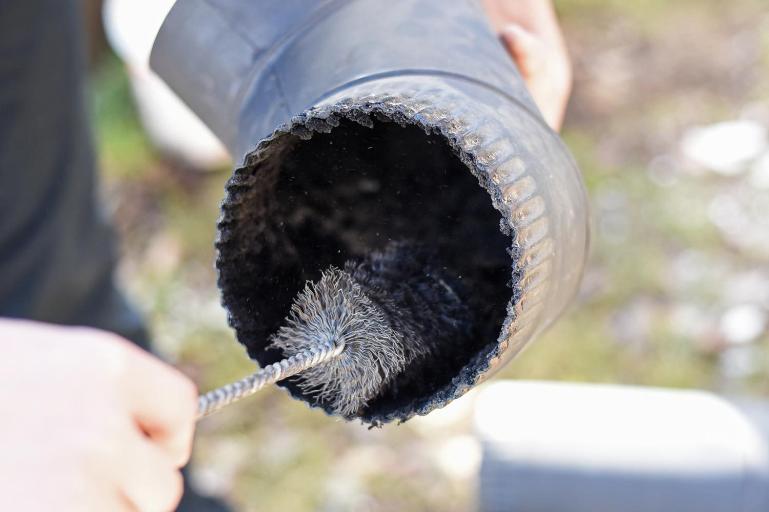 Man Cleaning and Sweeping Chimney Pipe Outside