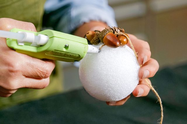applying hot glue on foam ball with glue gun