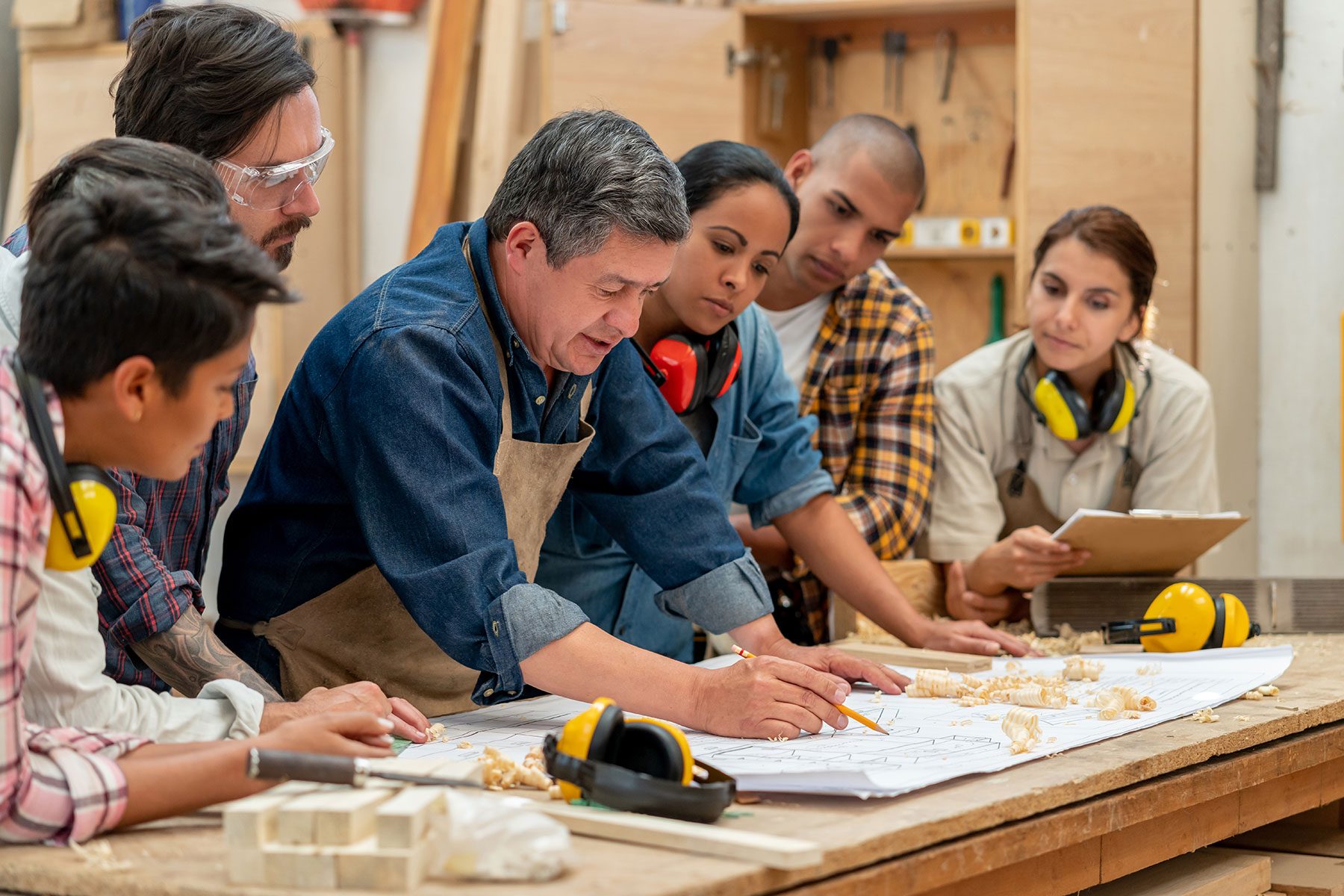 Group of workers at a furniture factory looking at a blueprint