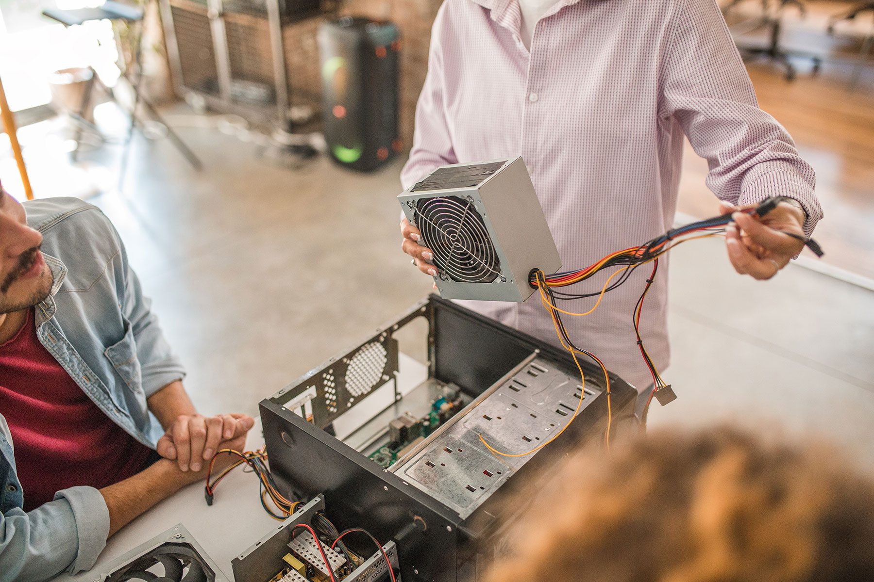 Close-up of female teacher's hands holding computer parts while giving a lesson to students