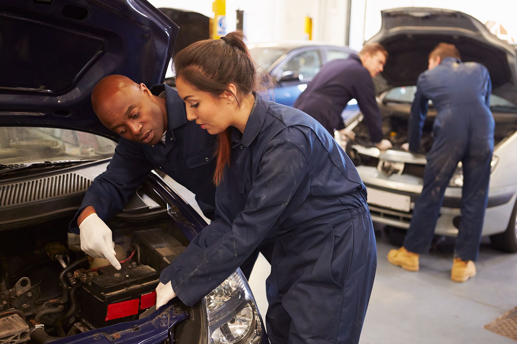 Teacher Helping Student Training To Be Car Mechanics