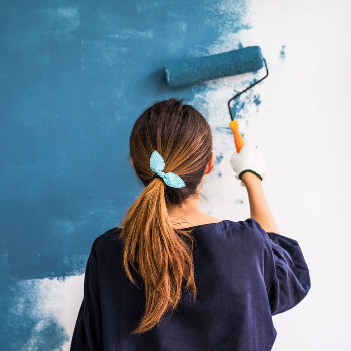 Young Asian Happy Woman Painting Interior Wall With Paint Roller