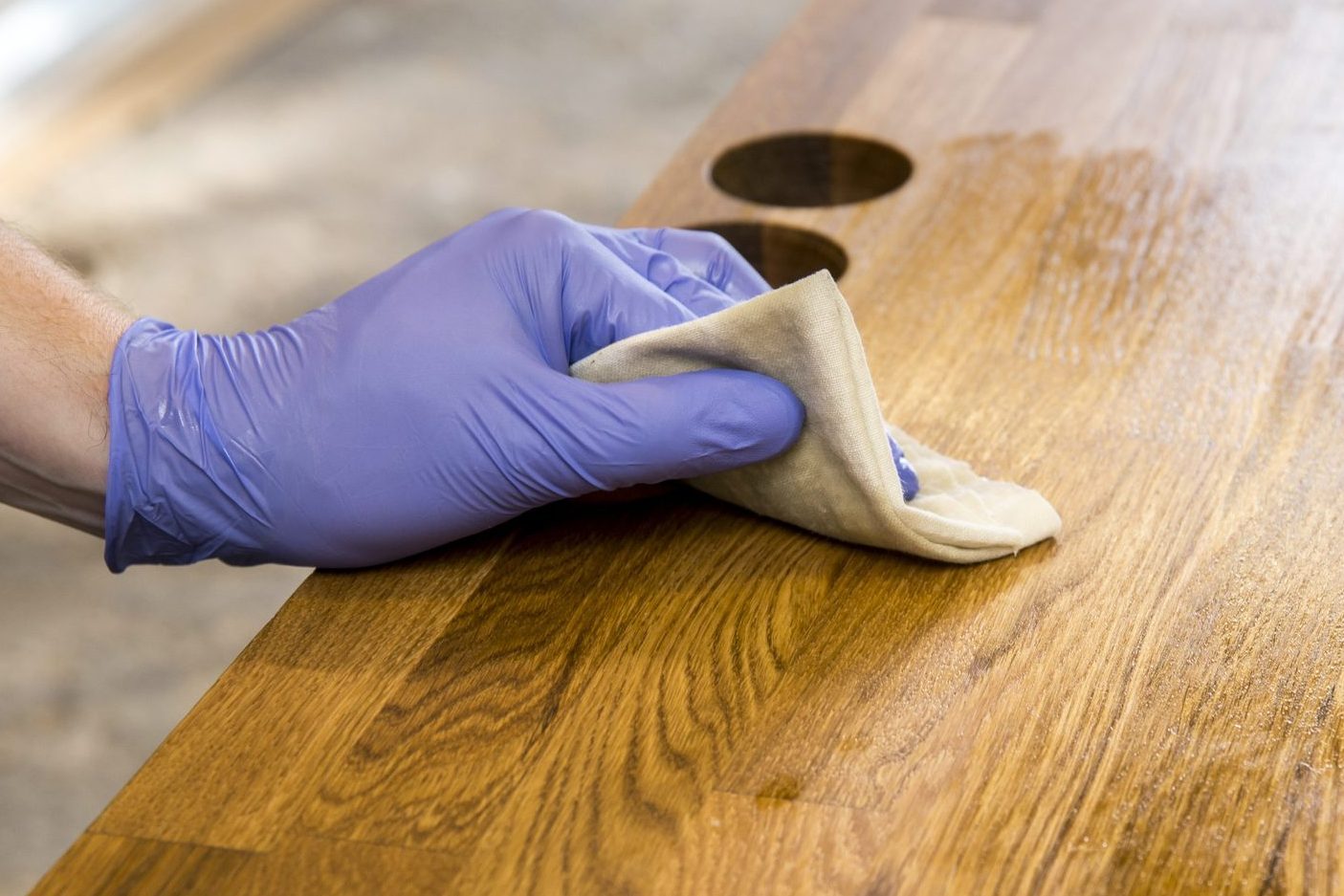 Person working, rubbing oiling with linseed oil natural wooden kitchen countertop before using. Solid wood butcher block countertop maintenance concept.