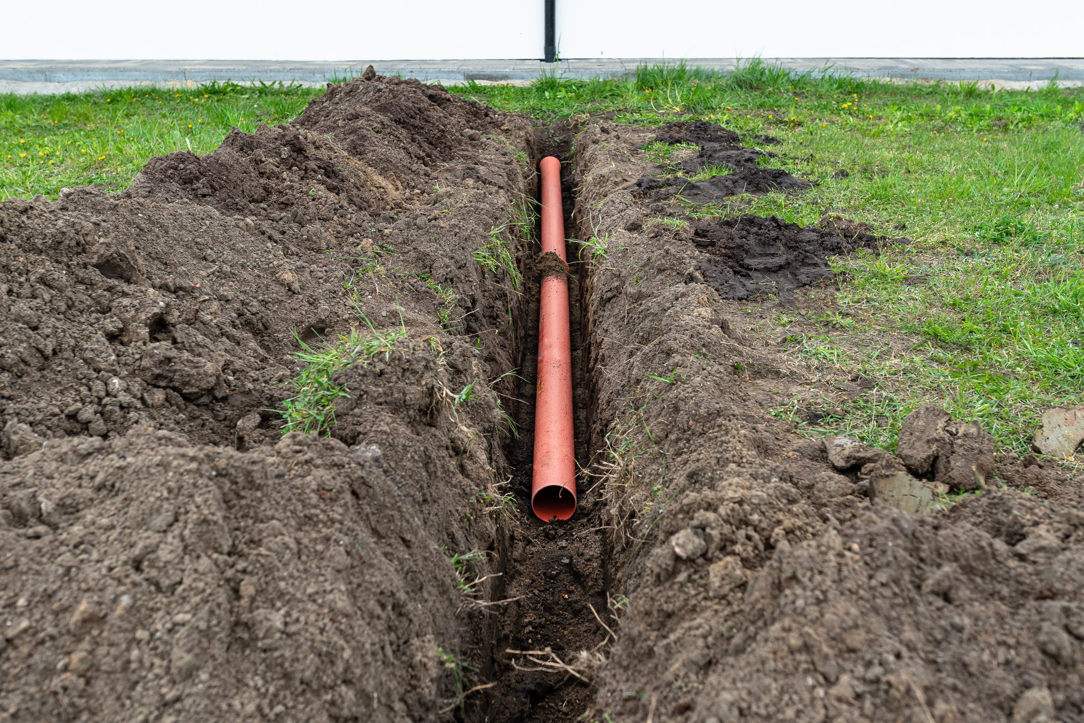 Orange PVC pipe buried in the ground connected to the gutter, used to connect to the drainage pipe.