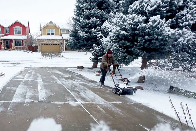 A man driveway blowing out snow from the driveway