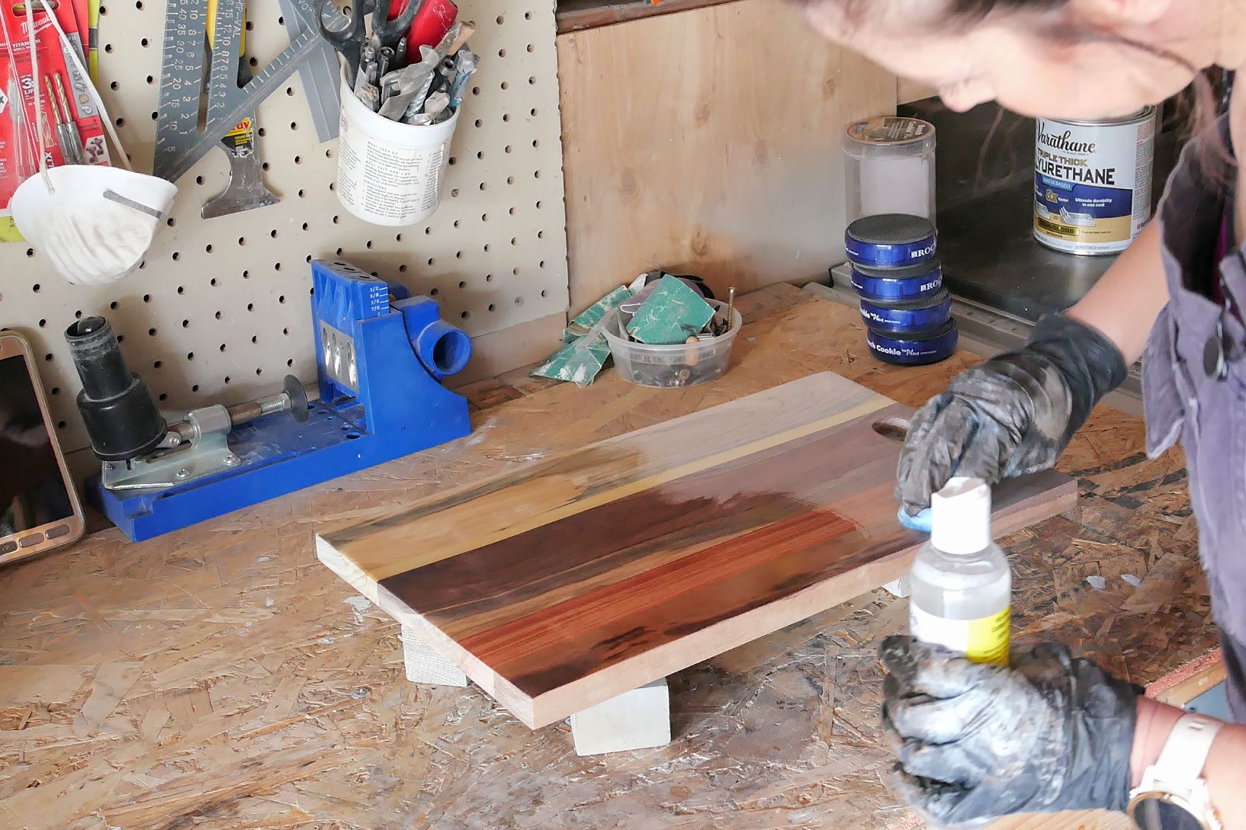 A woman is working on a piece of wood in a workshop.