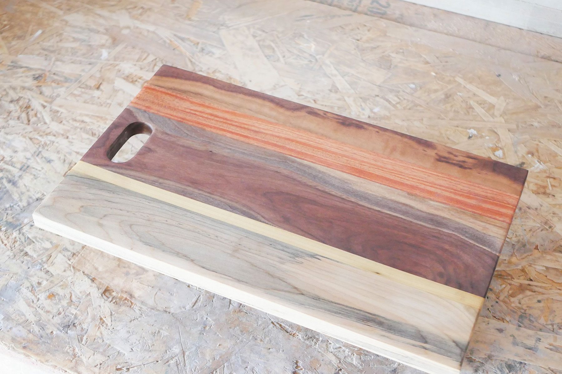 A wooden cutting board sitting on top of a wooden floor.