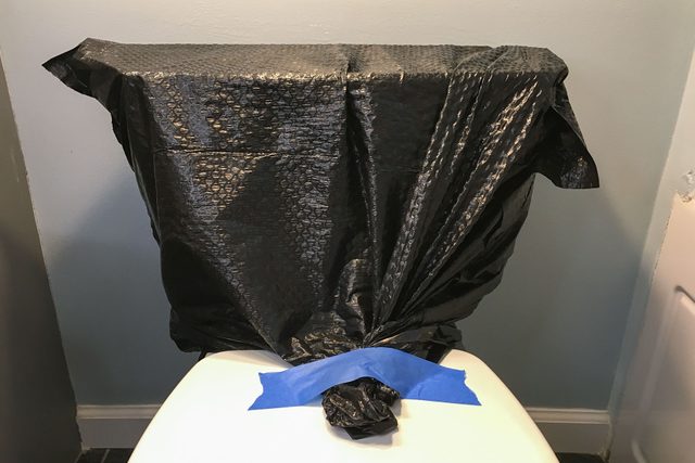 Trash bag covering the top of toilet