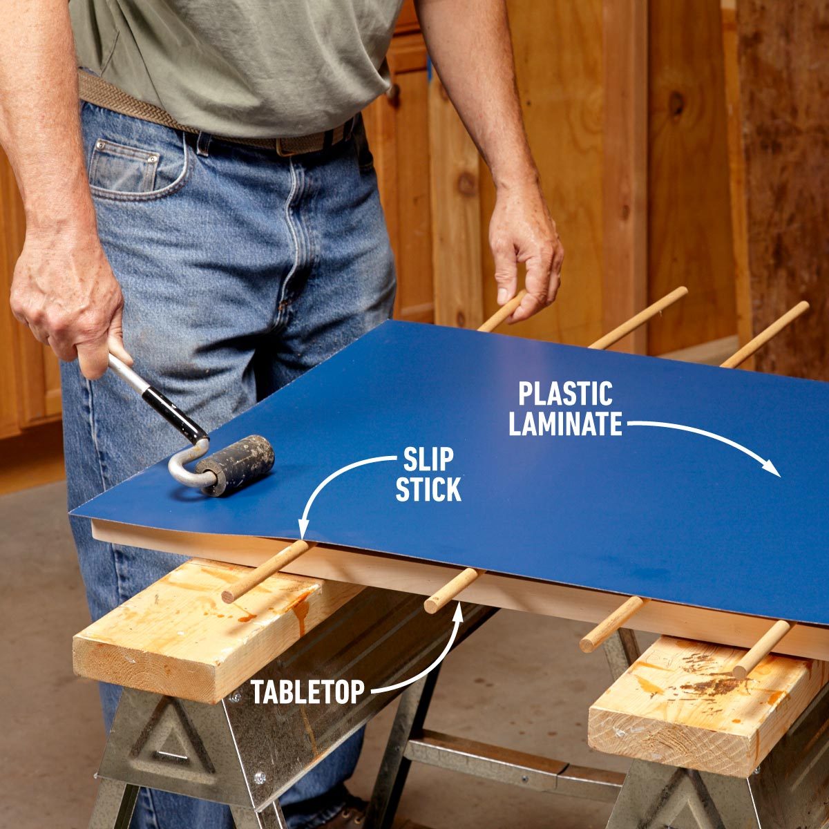 A man is working on blue laminating the top of wood.