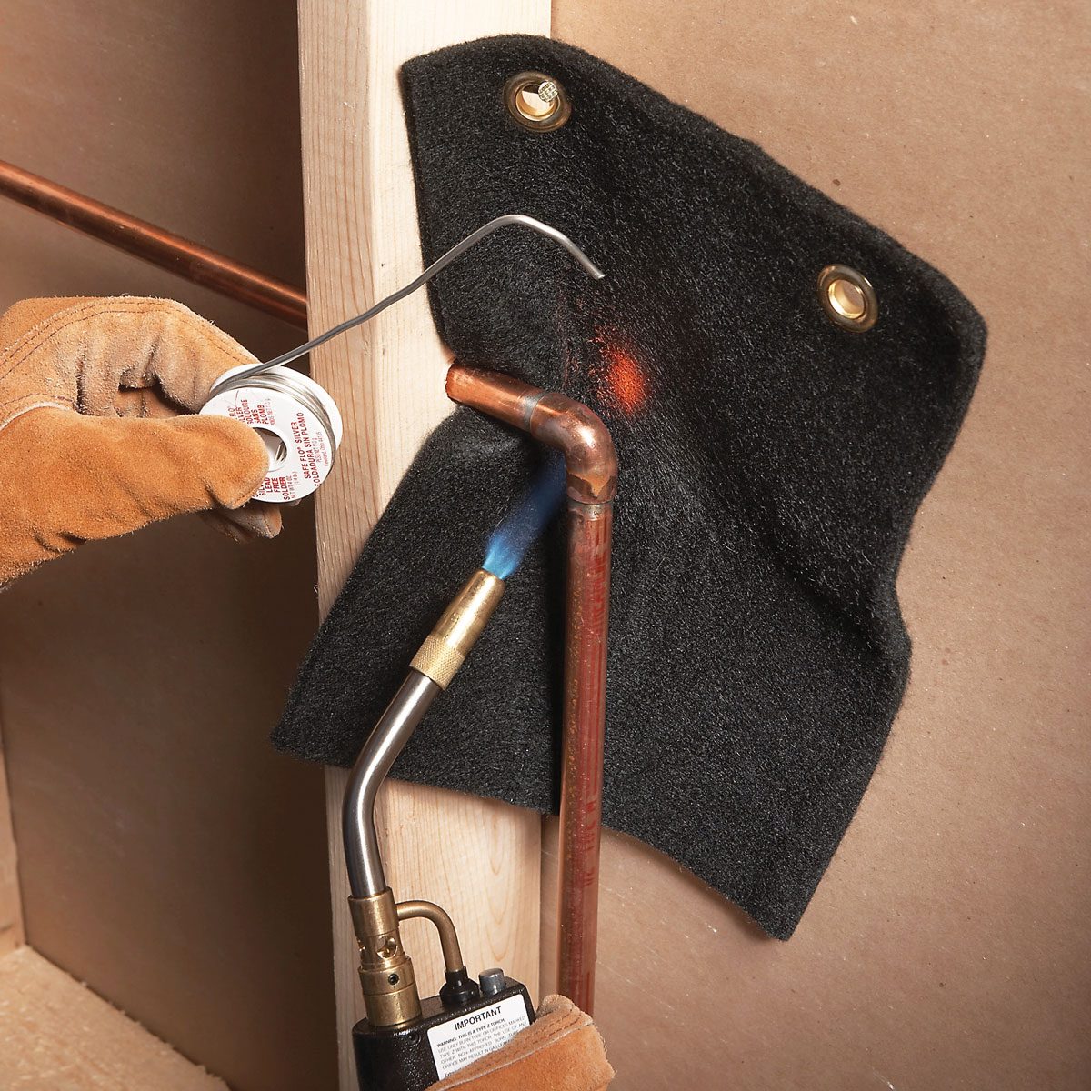 A person using flame protector while working on a copper pipe