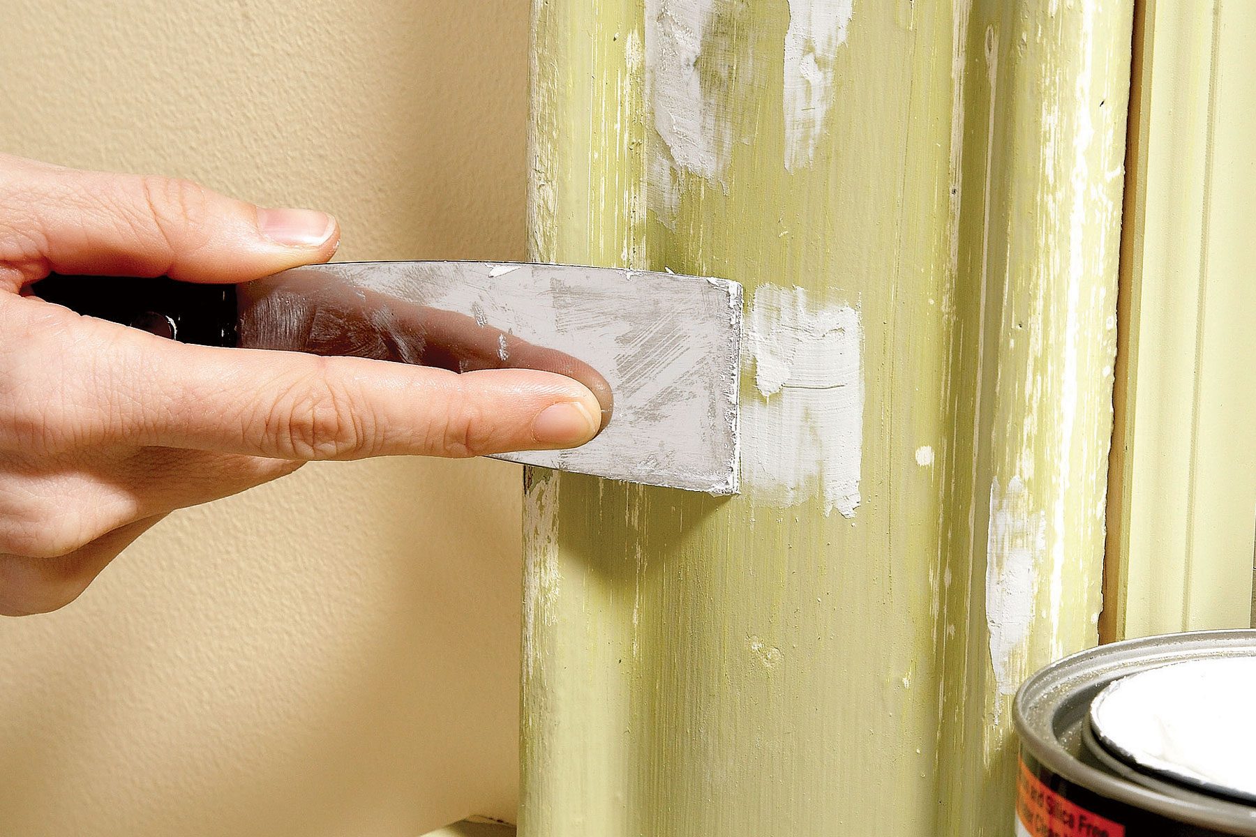 A person applying wood filler to fill holes in a pipe