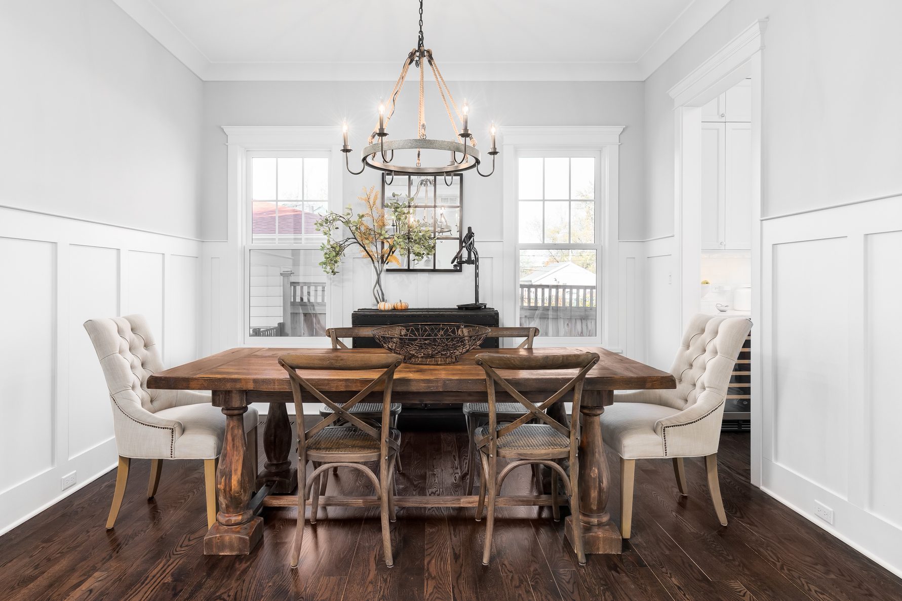 A farmhouse dining room with a rope chandelier hanging above the wood table.