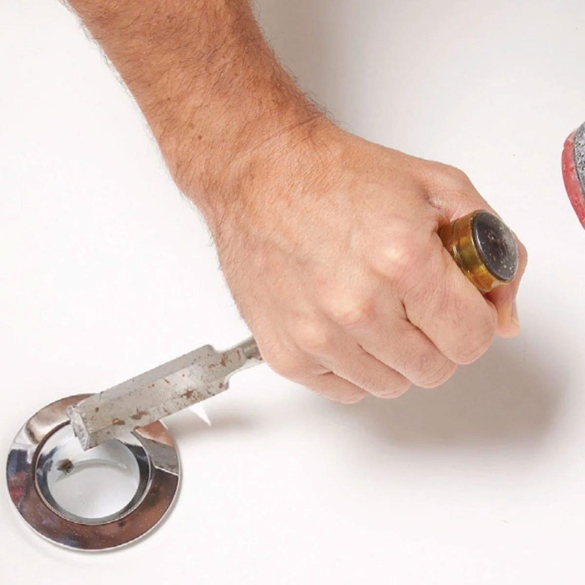 Loosening A Bathtub Drain Using A Chisel And Hammer With Hands