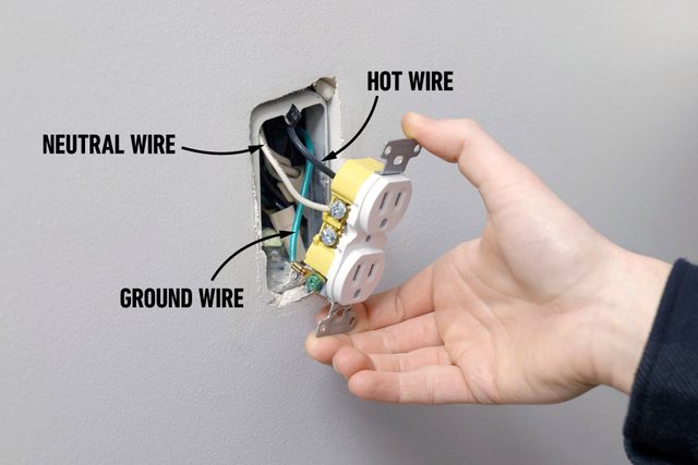 A person detaching the outlet from the wall electrical box