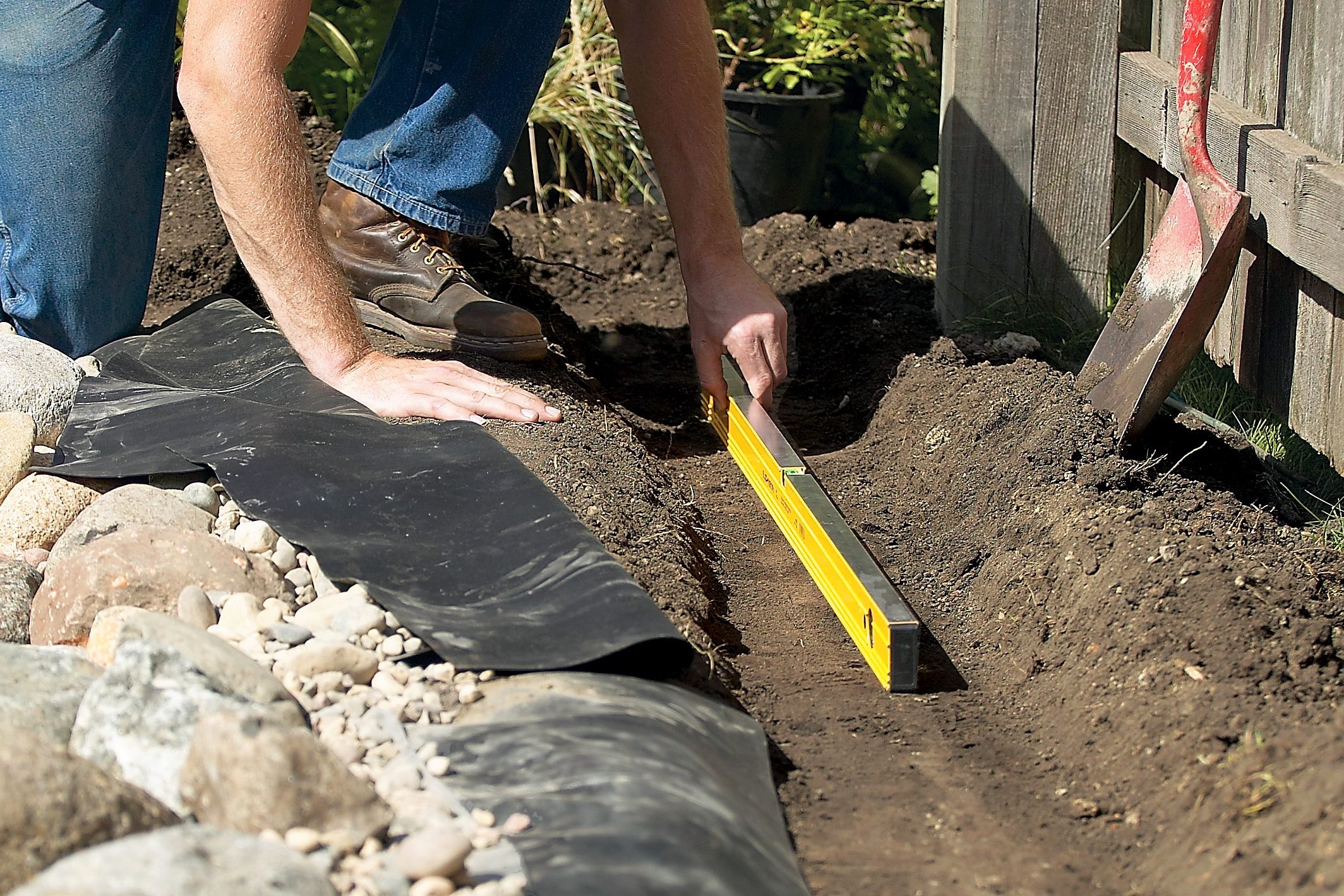 man making ridge in dirt around a pond