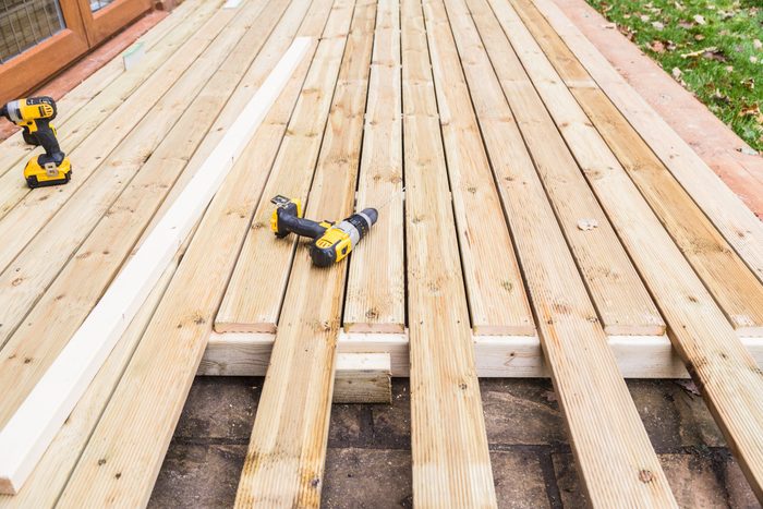 A new wooden, timber deck being constructed. it is partially completed. two drill can be seen on the decking.