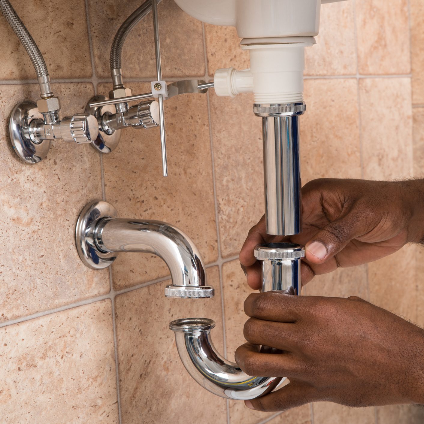 Plumber's Hand Fixing Sink In Bathroom