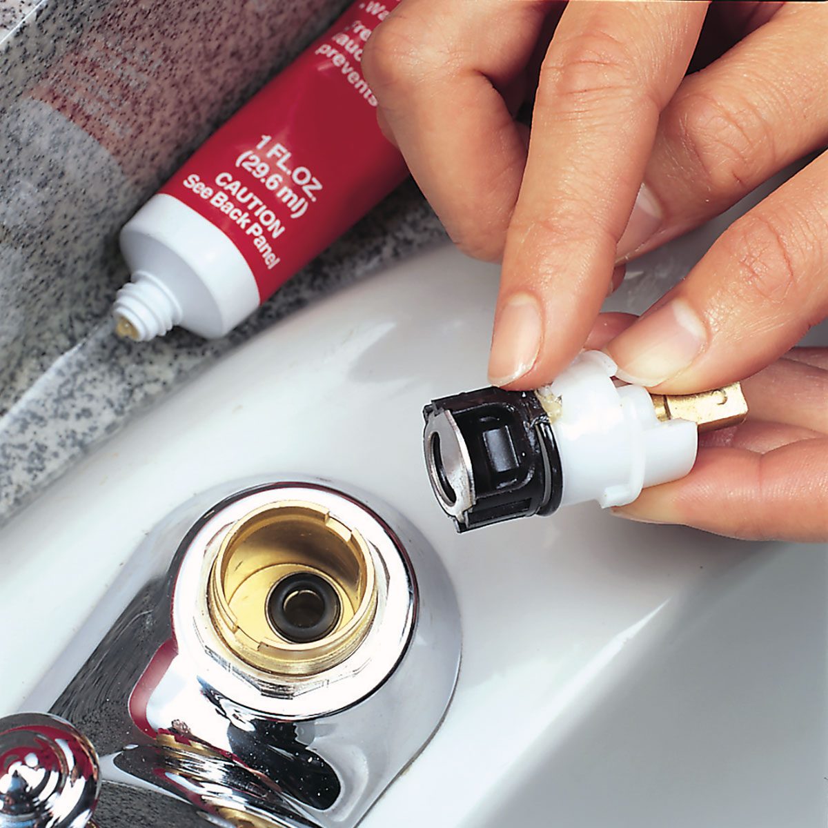 A close-up of a hand holding a white plastic faucet 