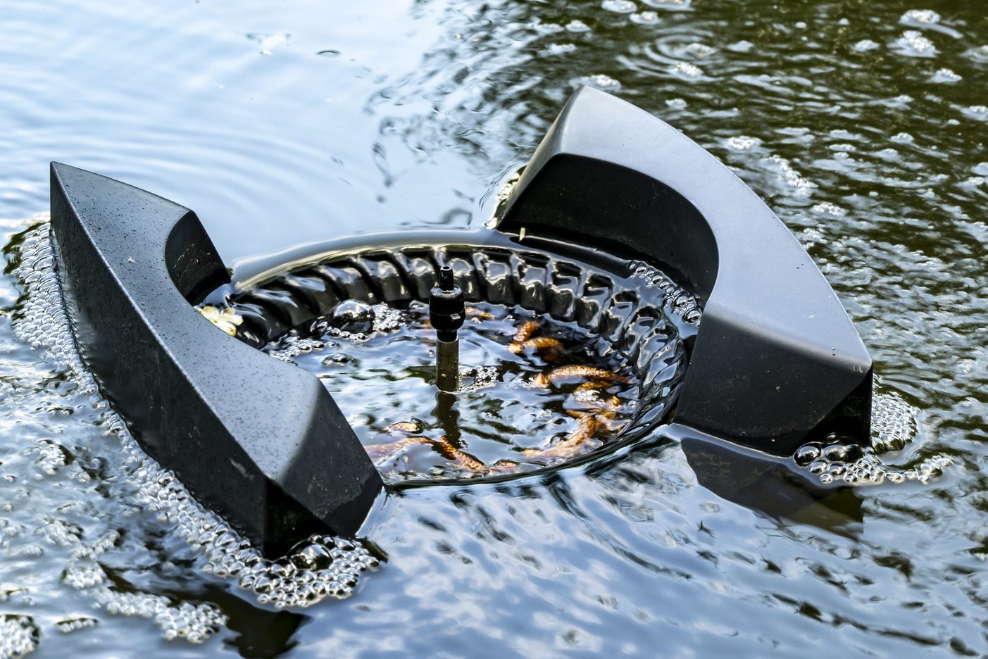 Water around Messner floating skimmer boils from air bubbles. Close-up. Skimmer floats on surface of water and collects leaves, dirt and other foreign objects from surface.