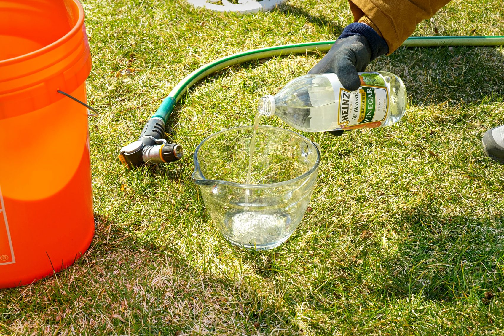 pouring distilled white vinegar into a glass beaker