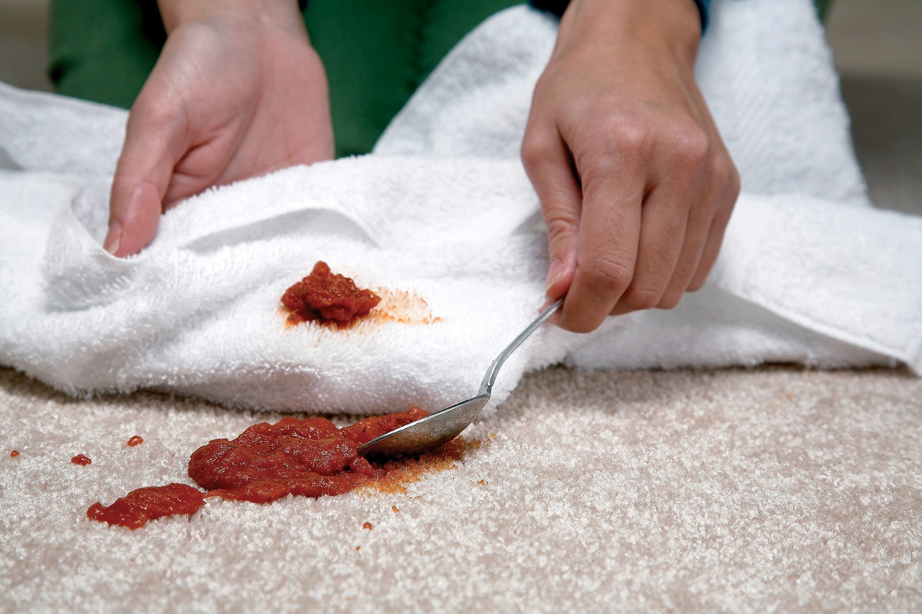 Someone picking spilled food from carpet with spoon