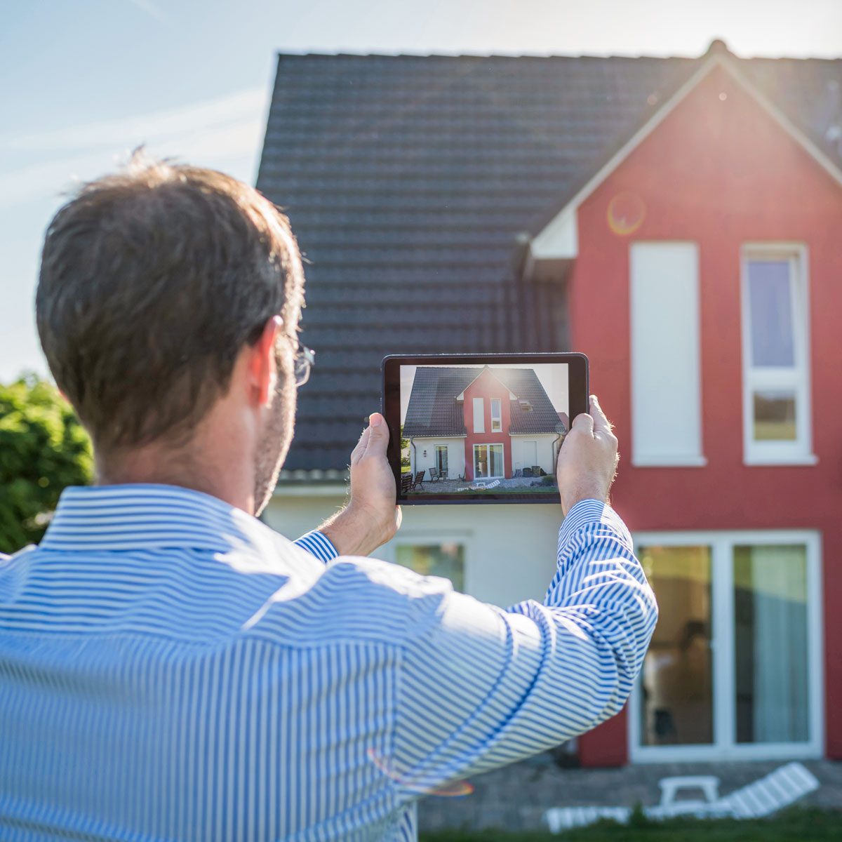 Man Photographing His House With Digital Tablet