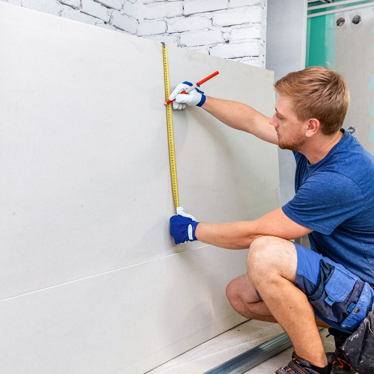 Man Measuring Plasterboard Sheet