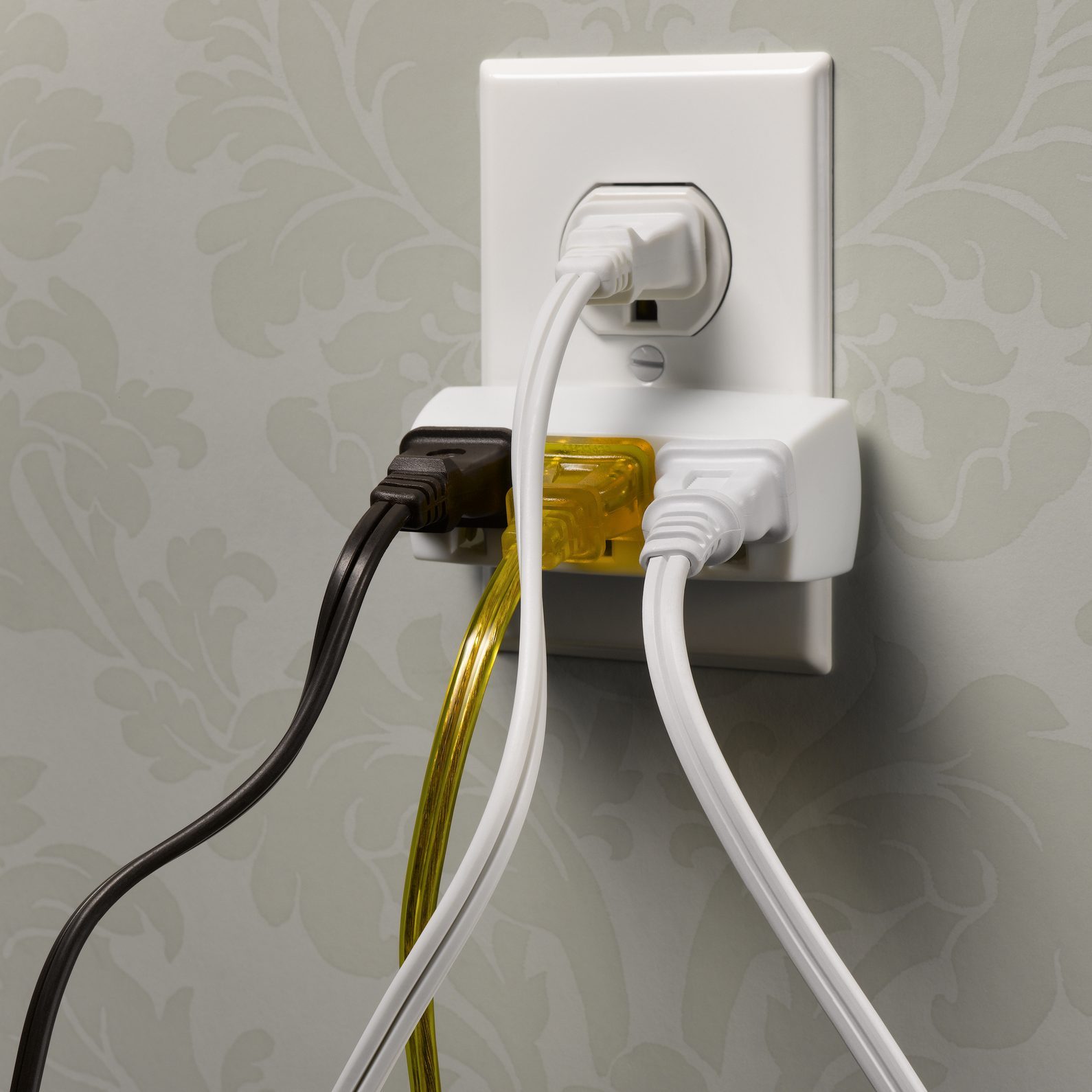 Electrical wall outlet overloaded with plugs, close-up