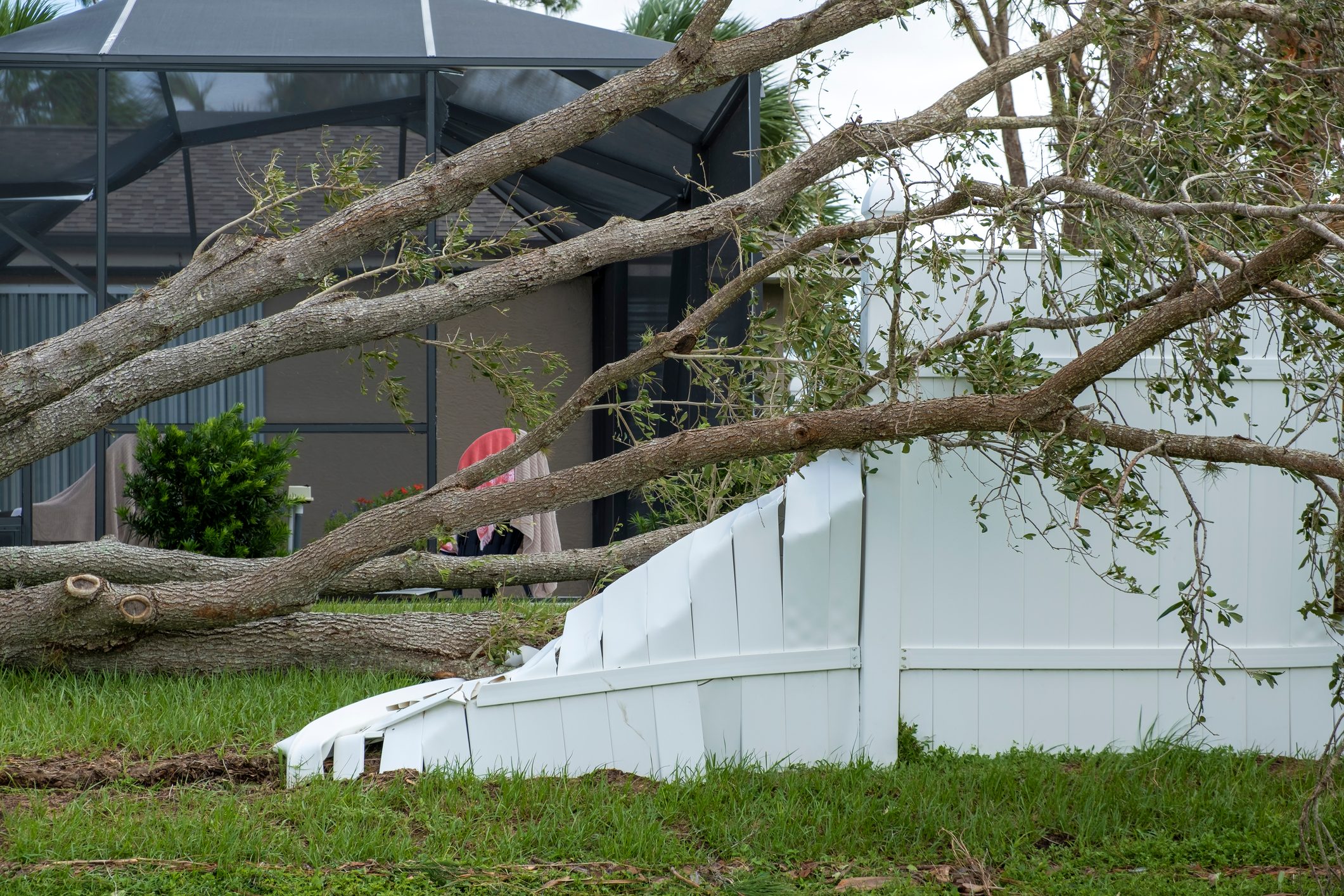 White plastic backyard fence damaged after hurricane winds in Florida