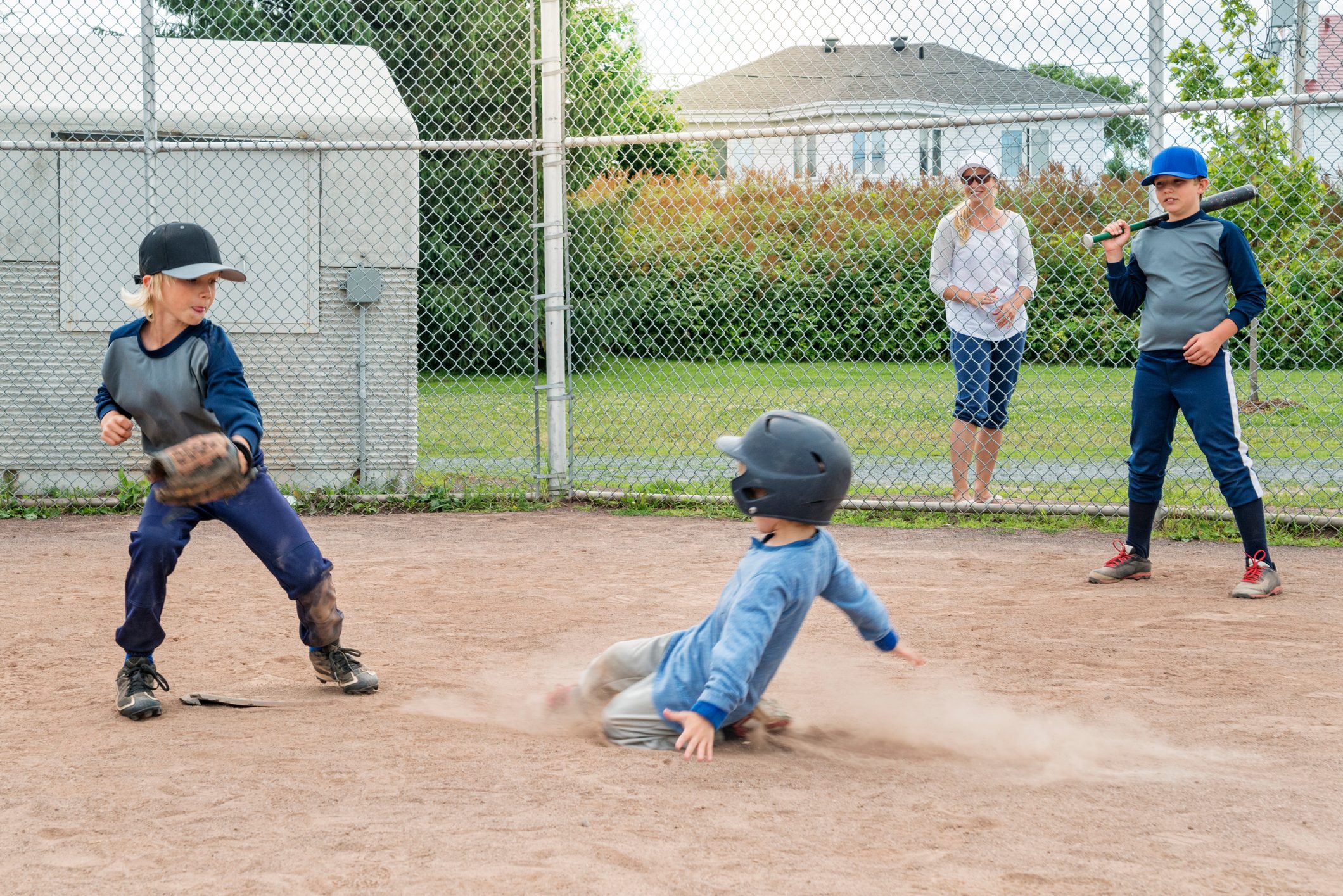 Kids playing baseball, one sliding to the plate