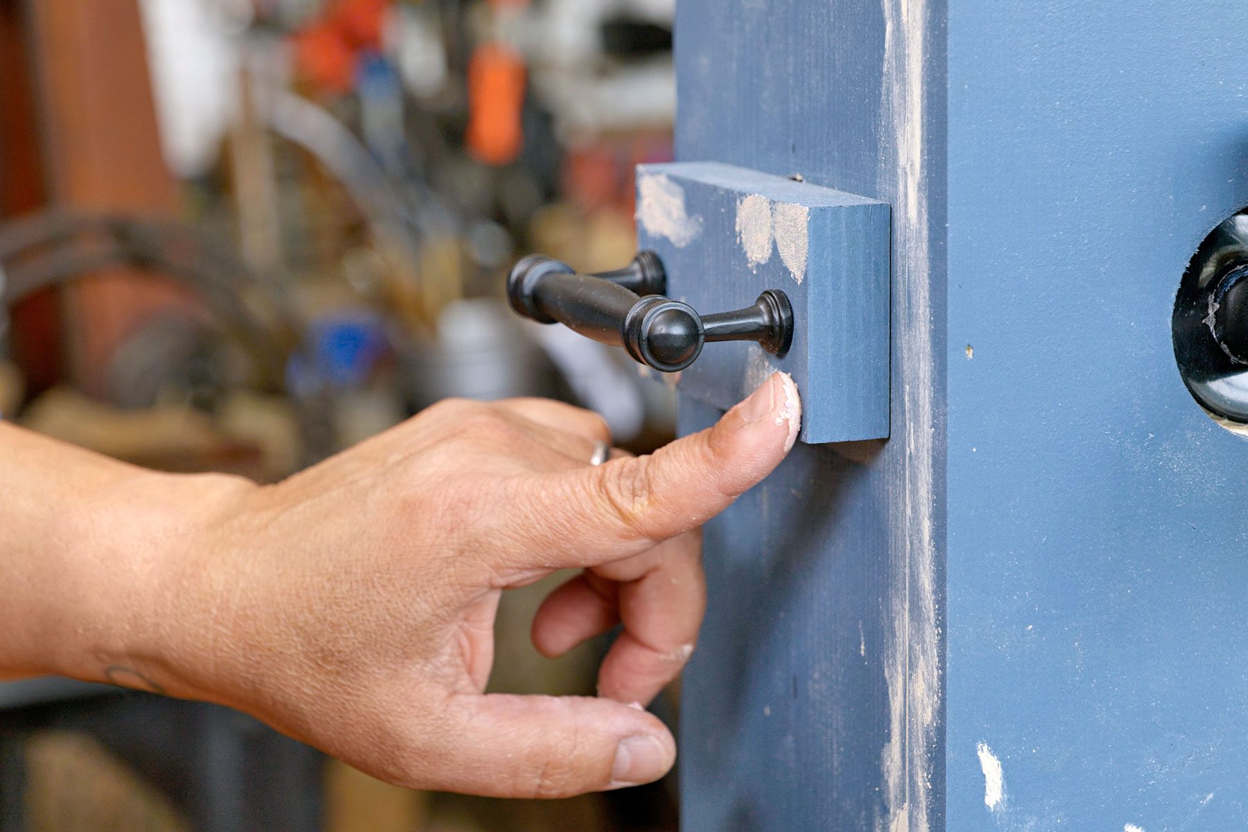 A hand is touching the part near filled and sanded screw/nail holes.