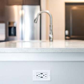Kitchen quartz countertop surface with electrical outlet on island in modern apartment