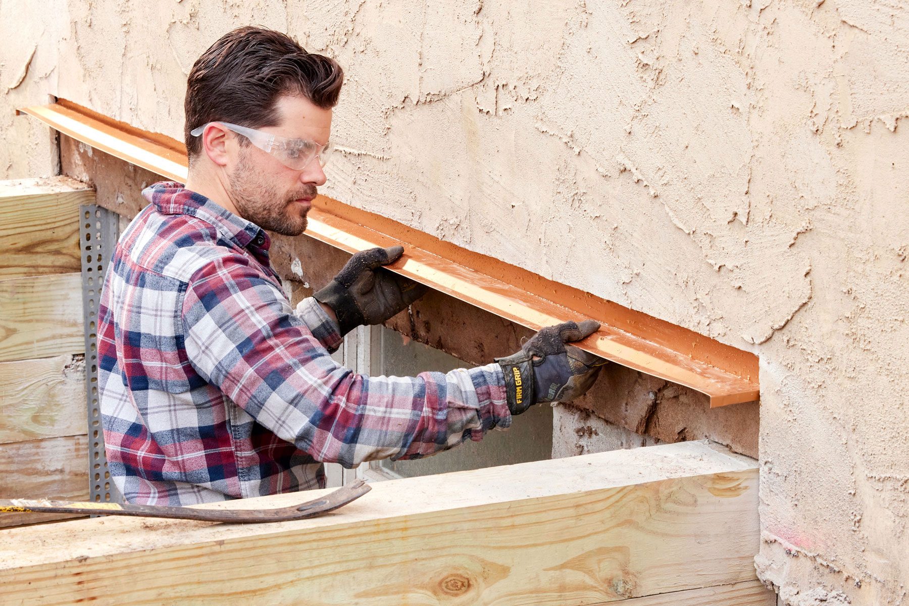 A man is installing drip edge flashing under the roof