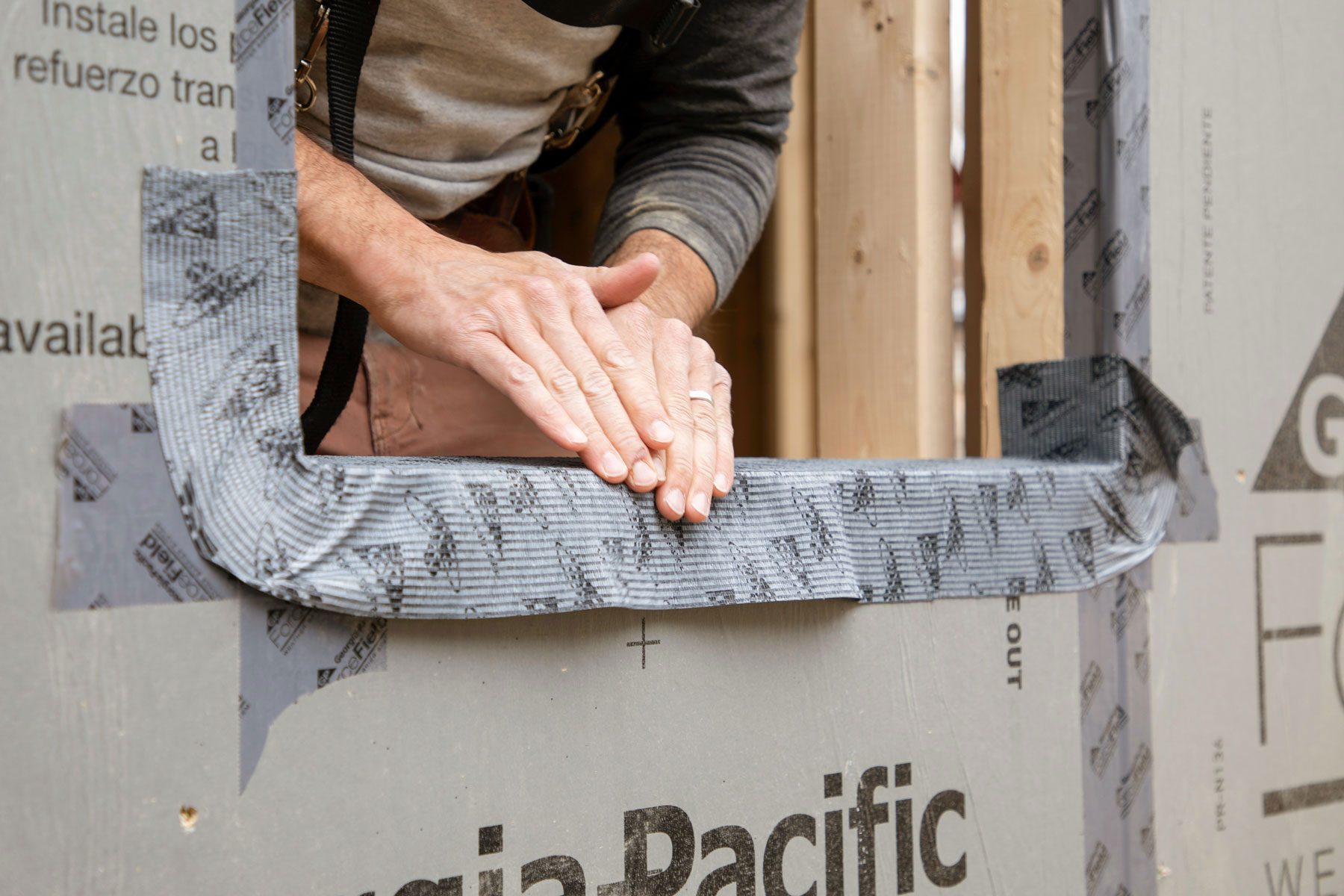 Hands can be seen installing drip cap flashing on window edge