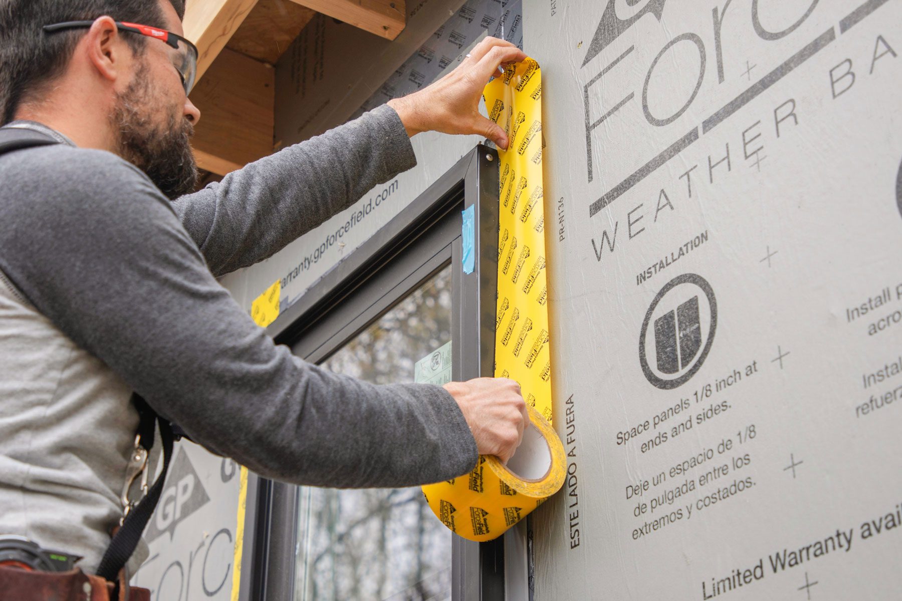 A man is using flashing tape at the edge of a window.